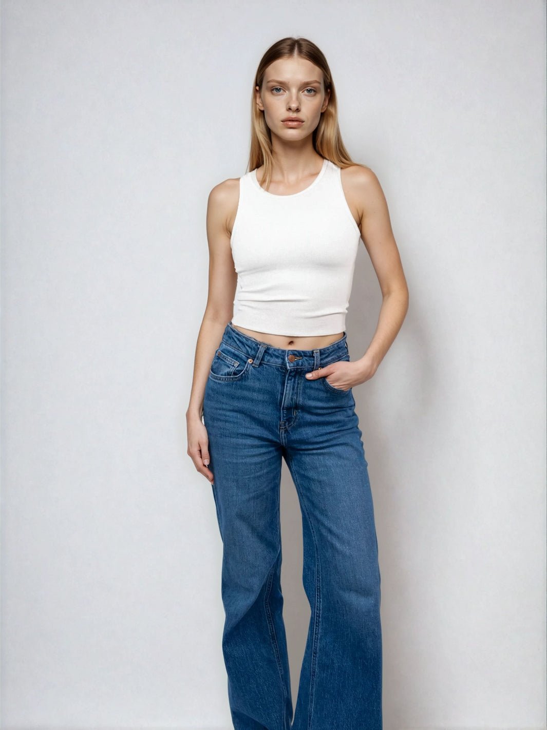 White high-neck sleeveless cropped tank with raw hem, fitted at the waist.