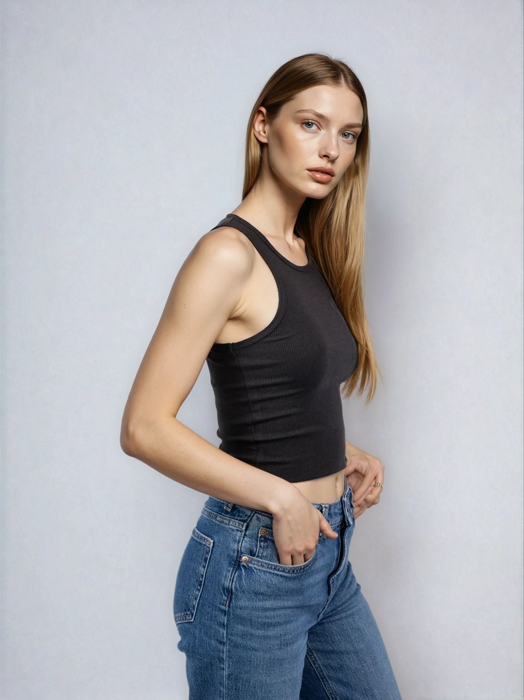 Black high-neck sleeveless cropped tank with raw hem, fitted and close to body.