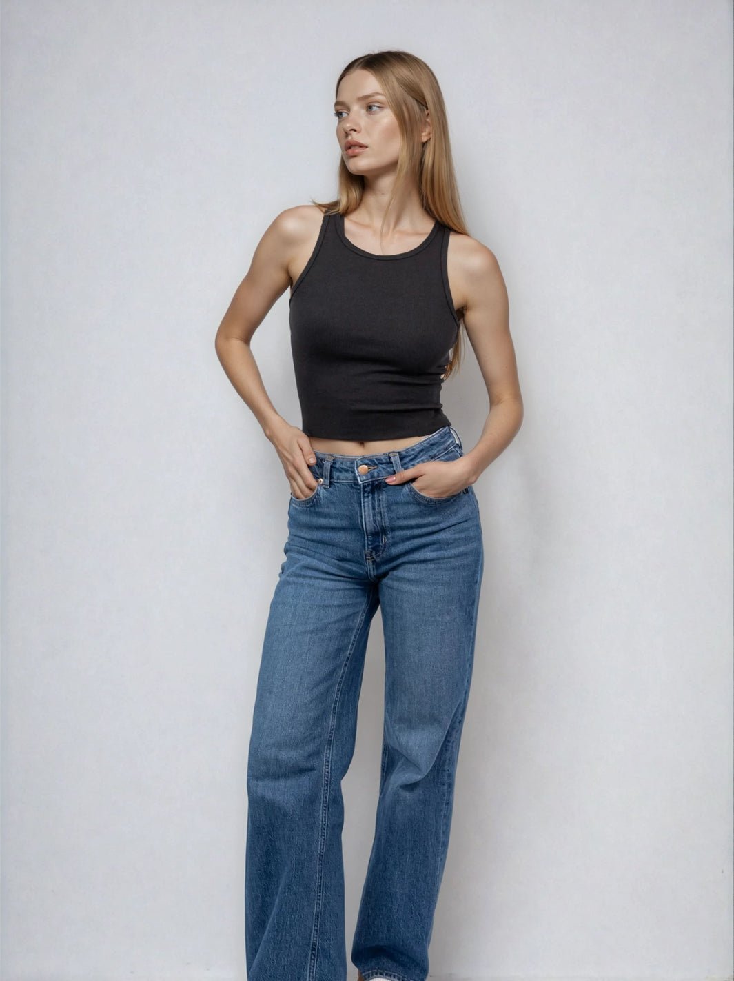 Black high-neck sleeveless cropped tank with raw hem edge, fitted silhouette.