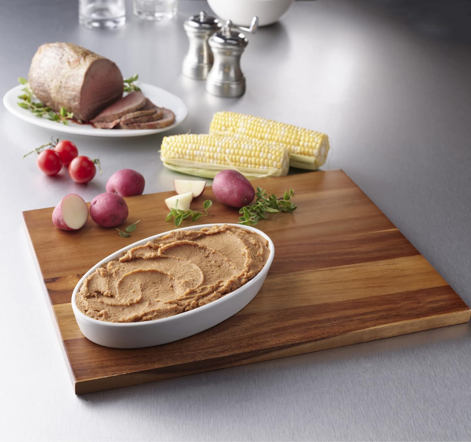 Homestyle beef puree in a bowl on a wooden board with vegetables and corn