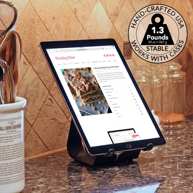 Fixed-angle iPad stand in dark finish holding a tablet at a slight tilt