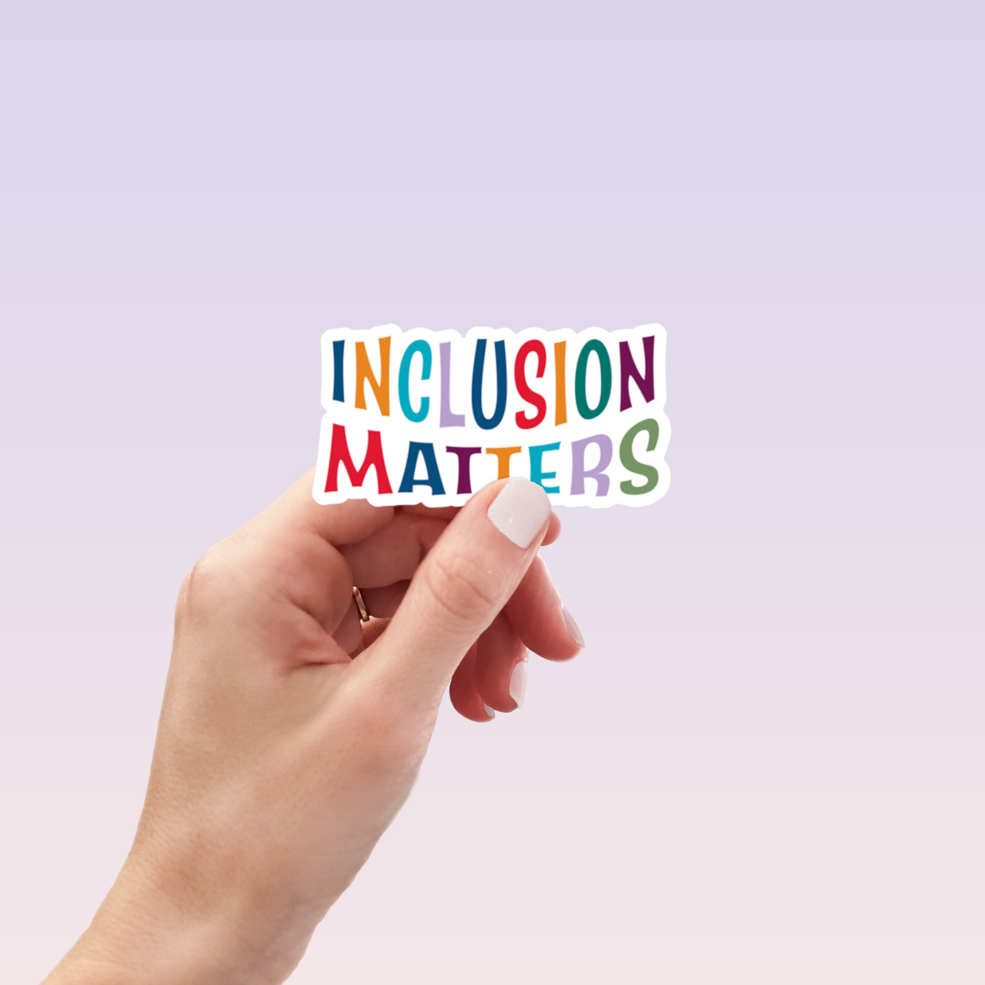 Hand holding white die-cut Inclusion Matters sticker with multicolor letters
