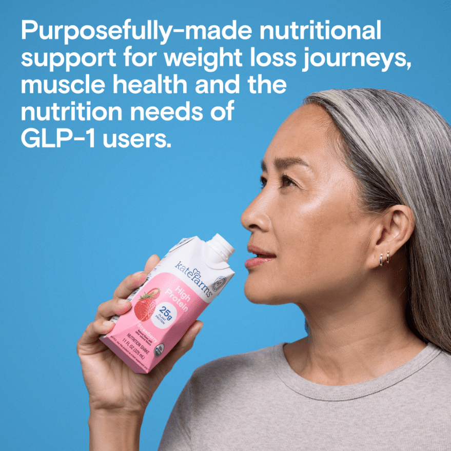 Kate Farms High Protein Strawberry nutrition shake bottle held near face