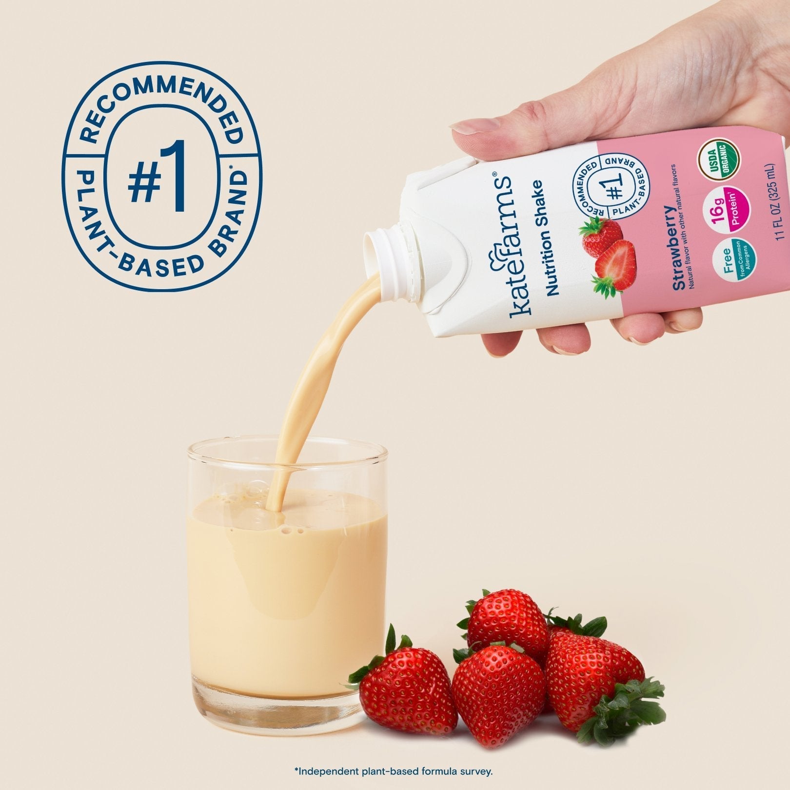 Hand holding Strawberry Nutrition Shake carton, pouring into a glass with strawberries