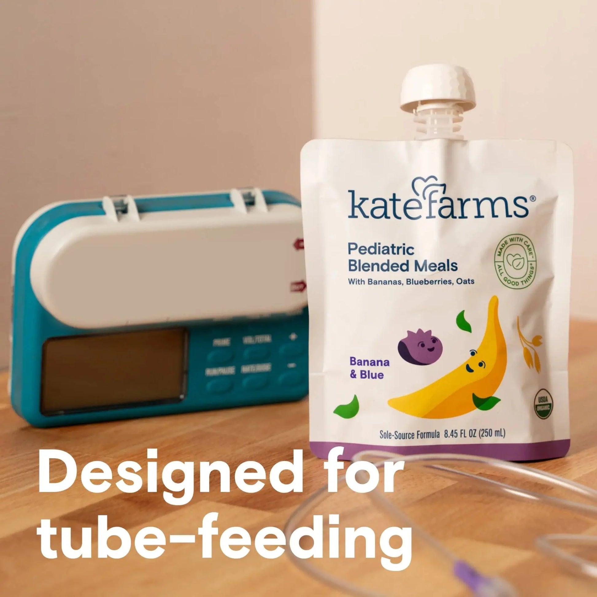 Banana & Blueberry pediatric blended meals pouch standing near tube-feeding equipment
