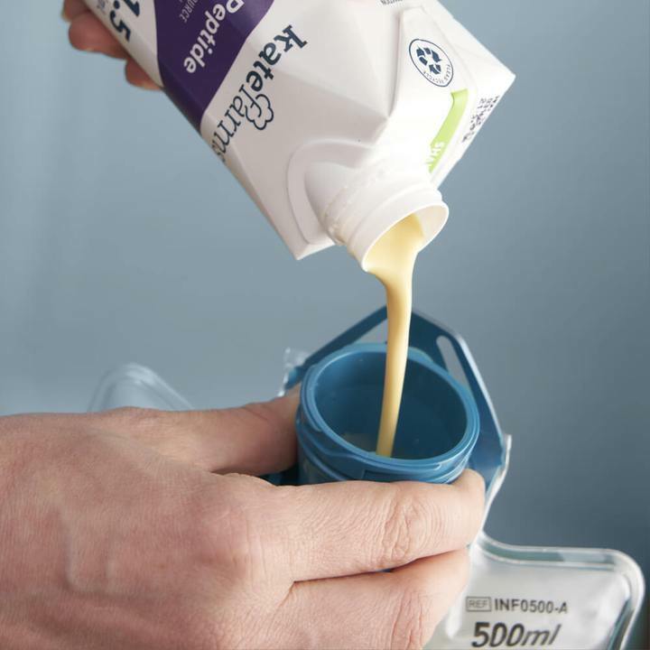 Vanilla peptide formula poured from carton into cup, light yellow liquid