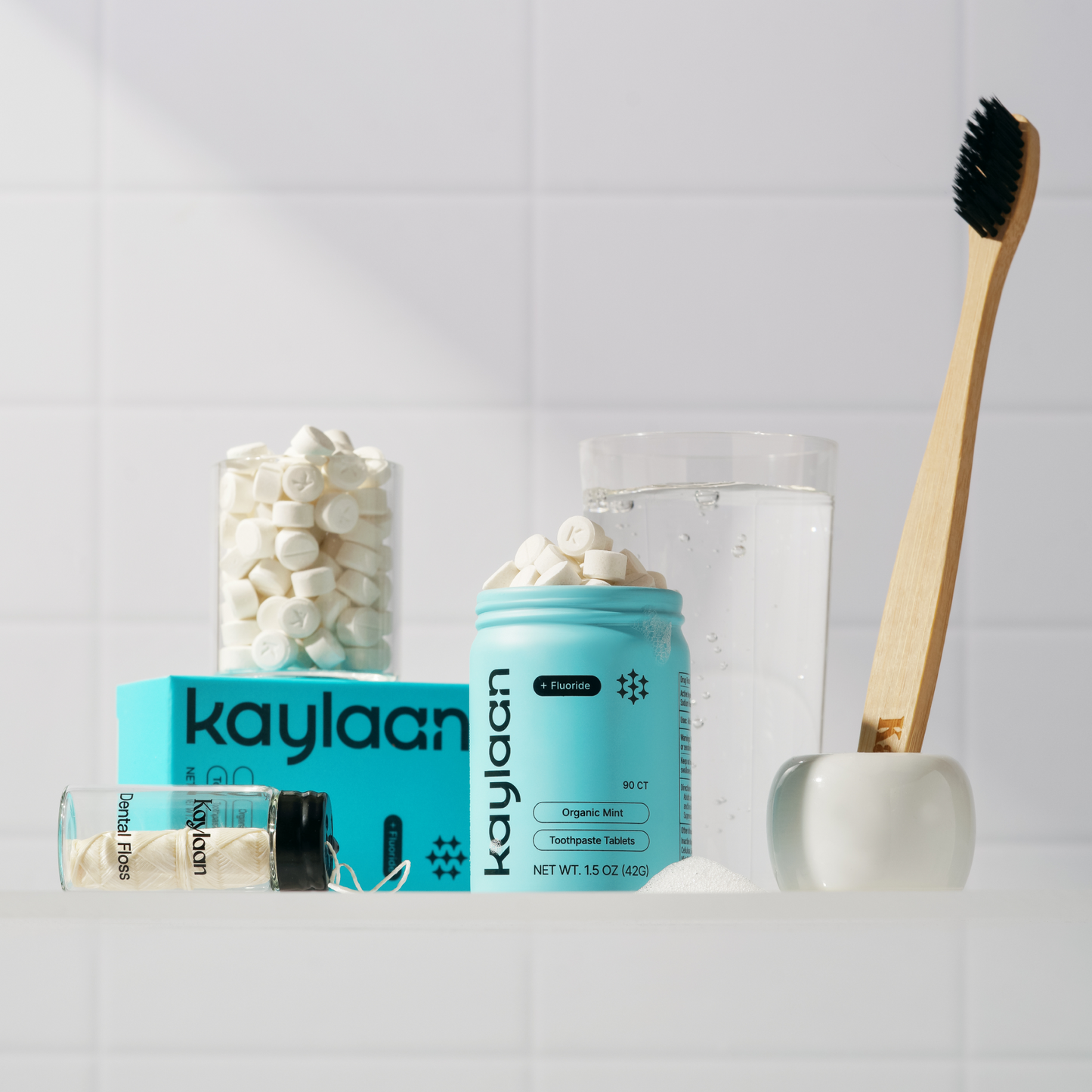 Oral care kit with fluoride toothpaste tablets, jar, and wooden toothbrush with black bristles