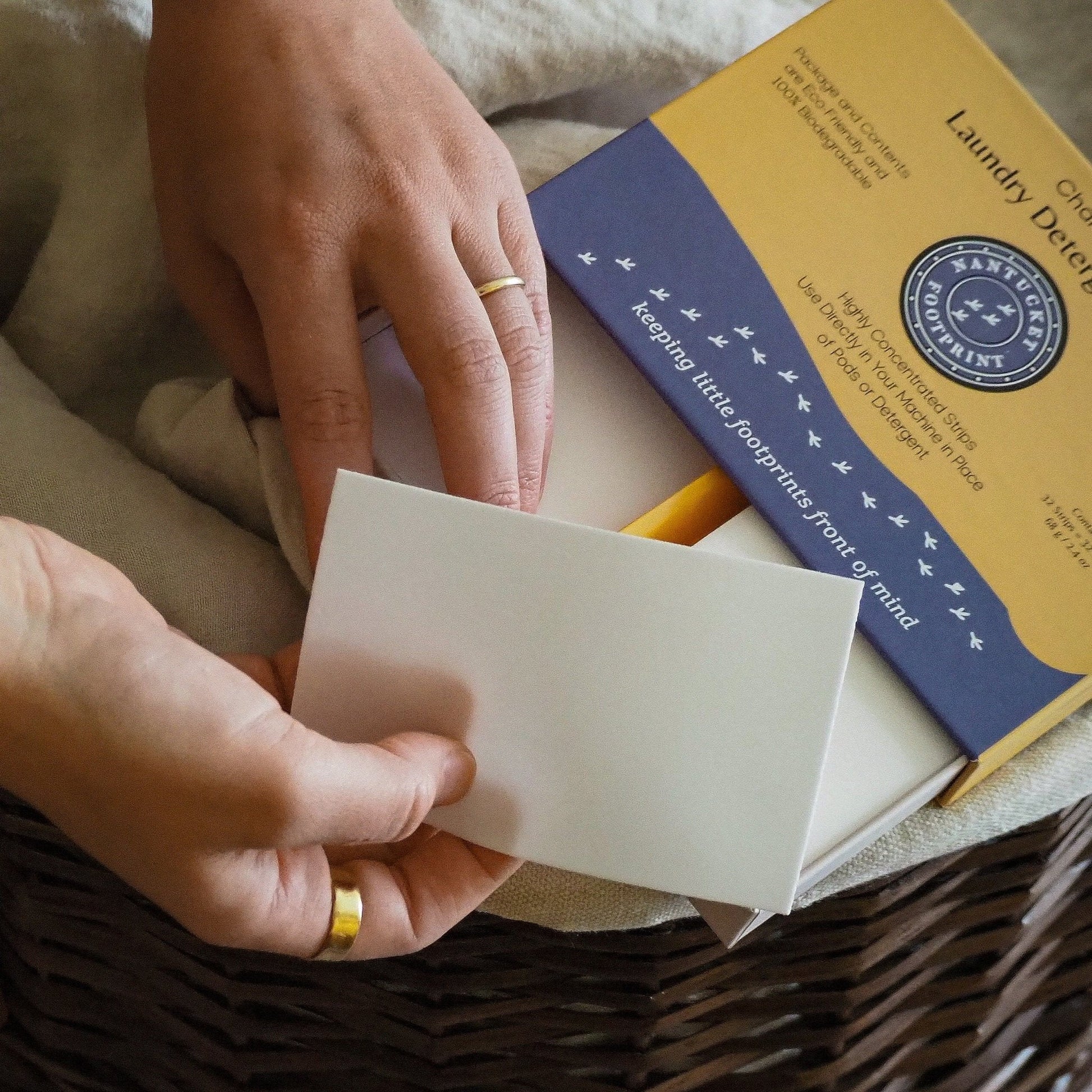 Laundry detergent strips pack, white sheet strip held in hands; chamomile scent
