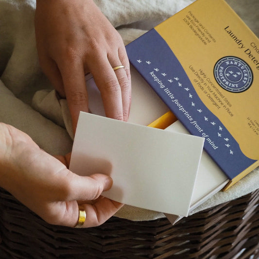 Laundry detergent strips pack, white sheet strip held in hands; chamomile scent
