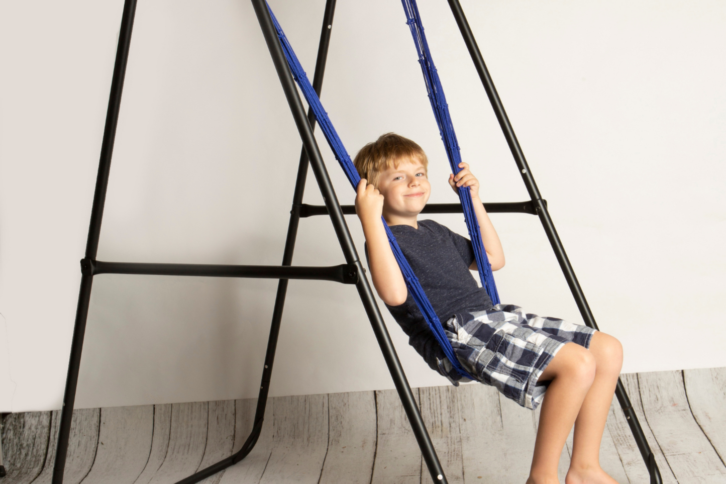 Kids hammock chair swing with blue woven rope and black stand frame, child gripping ropes.