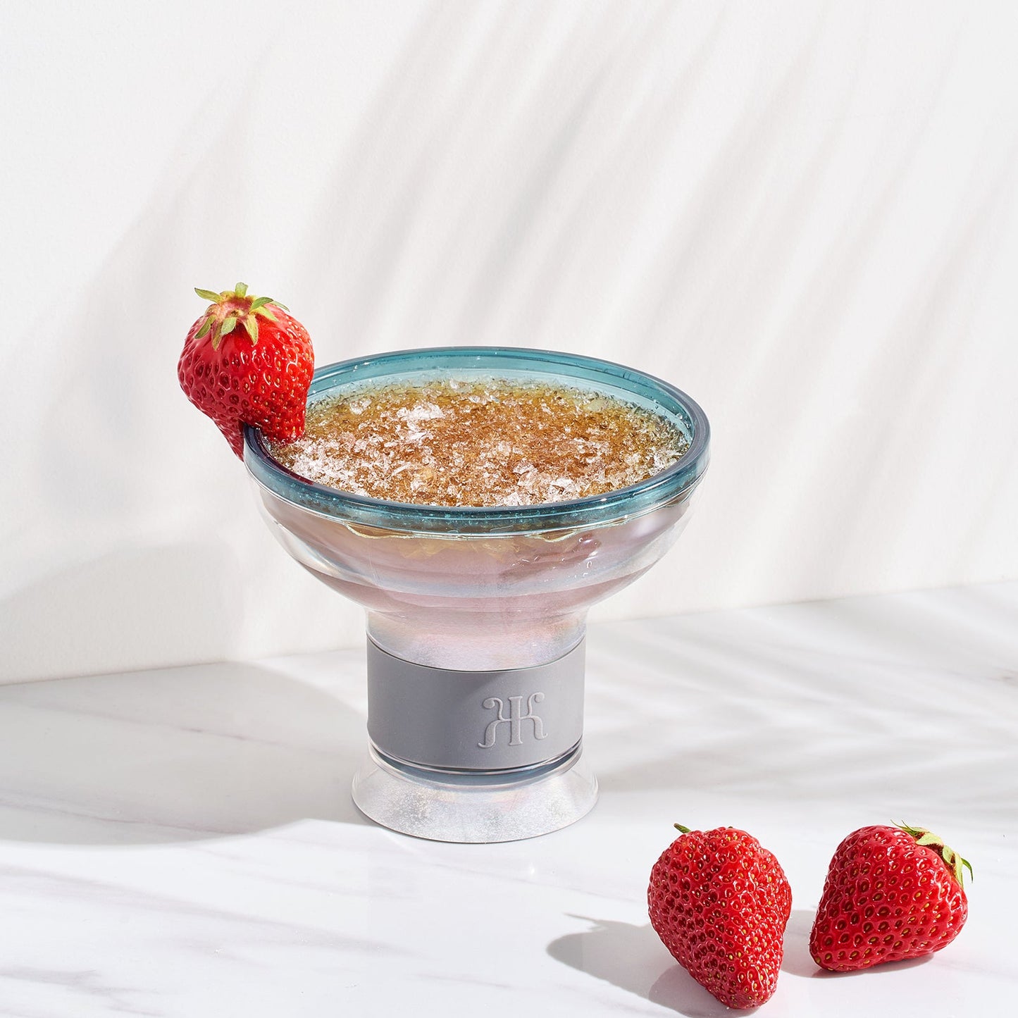 Acrylic cocktail chiller glass with ice, strawberry garnish, and pink drink filling.