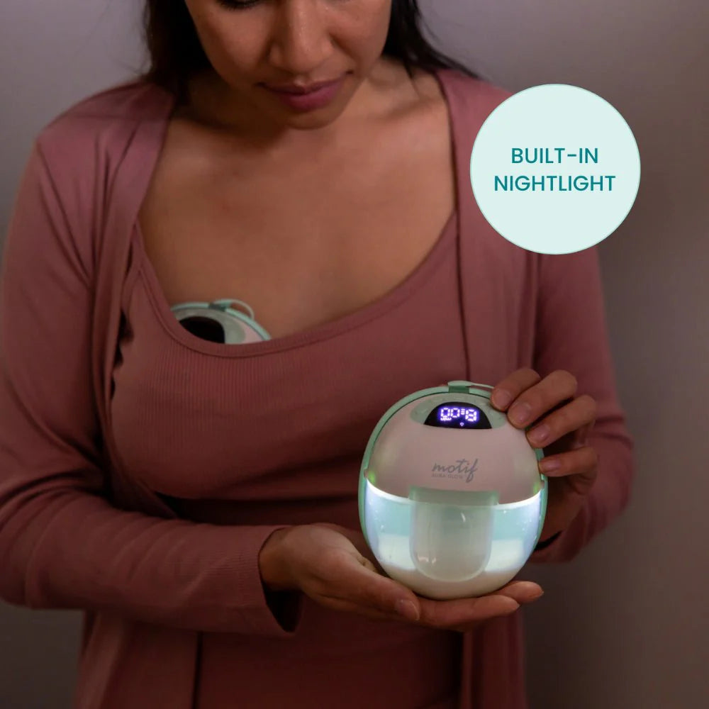 Wearable breast pump with illuminated display, mint-tinted dome held in hands
