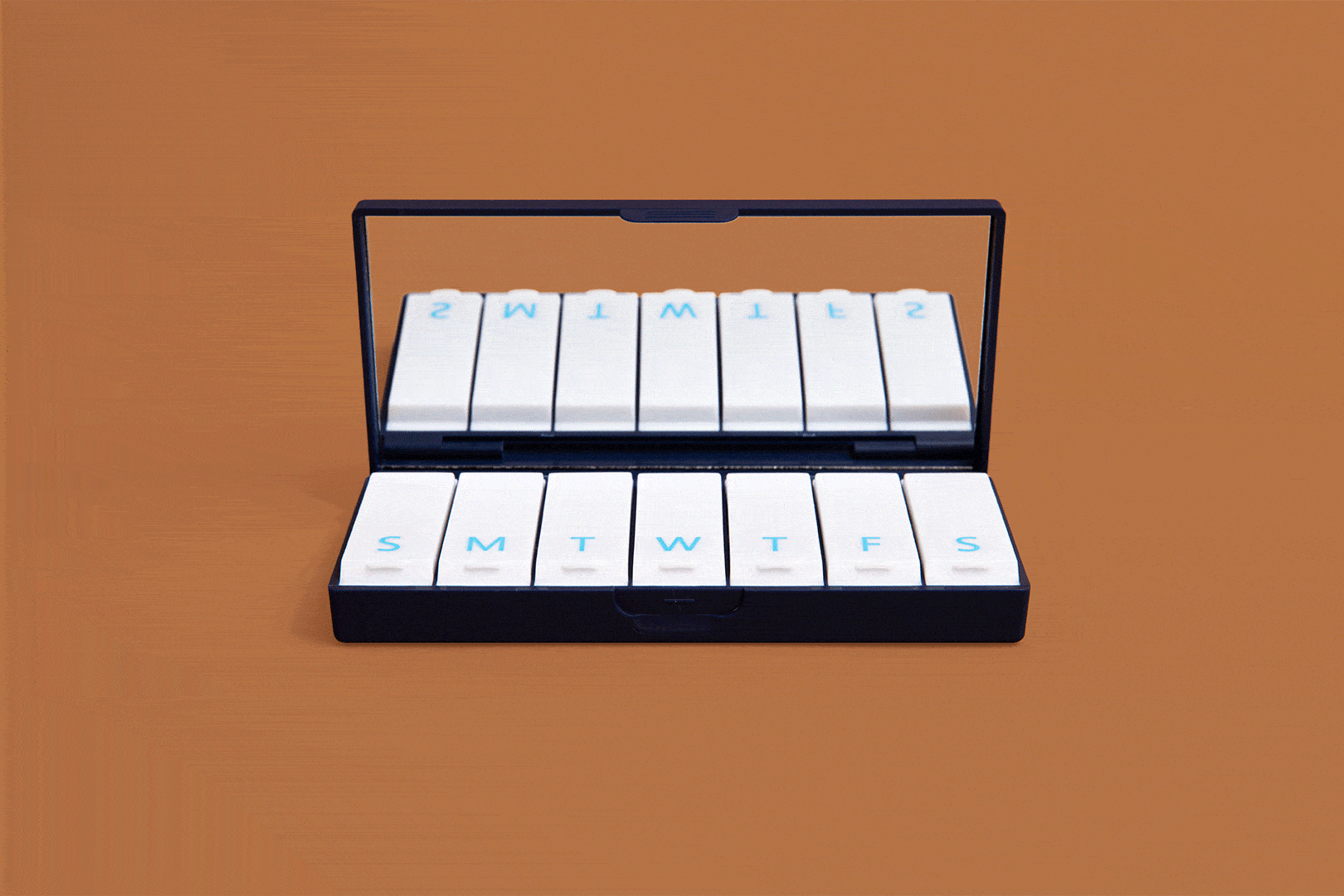 Navy blue pill box open with white labeled day slots