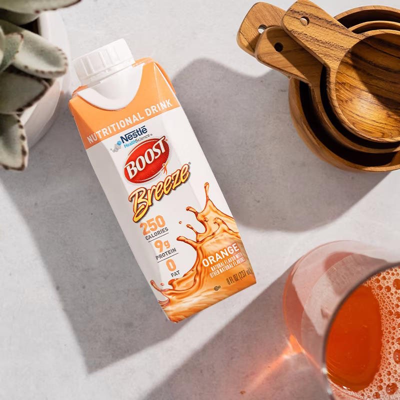 Orange Boost Breeze nutritional drink carton with glass of orange drink, front view