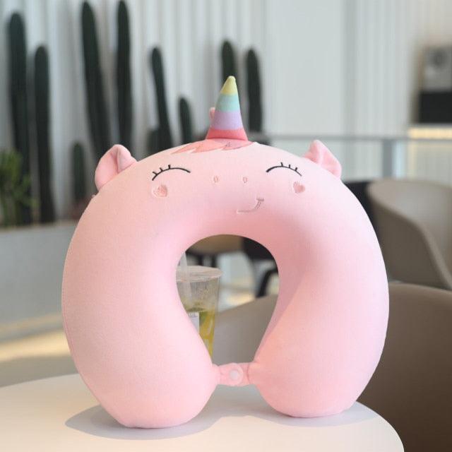 Pink U-shaped unicorn neck pillow with small horn and embroidered eyes