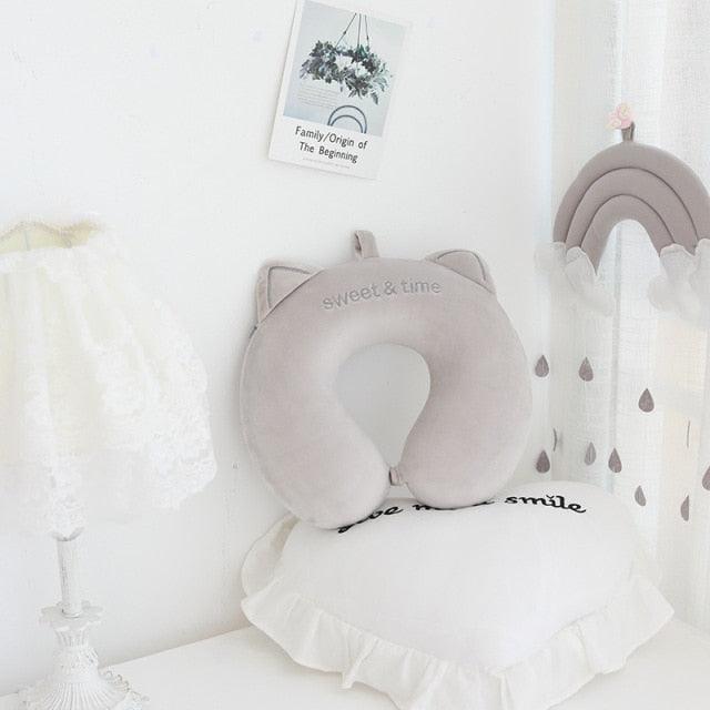 Light gray U-shaped cat neck pillow with ears and embroidered smile