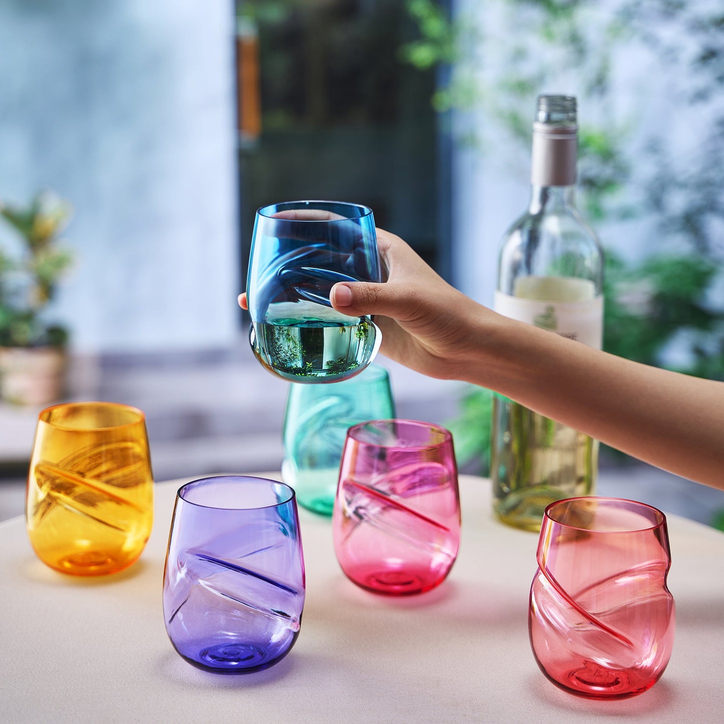 Stemless acrylic wine glasses with finger-indent, mixed colors, one held up
