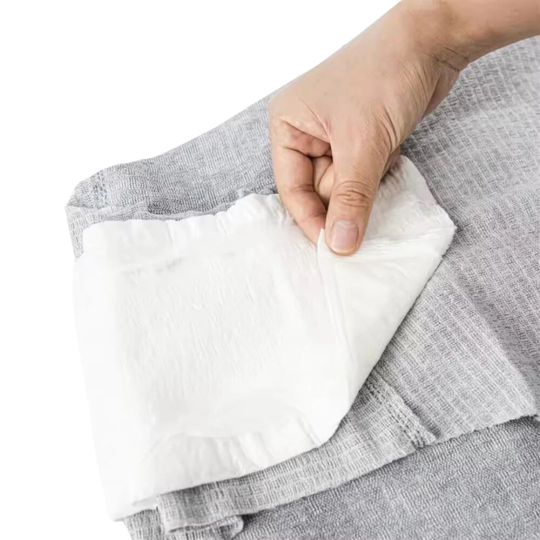 Hand adjusting white absorbent pad inside gray incontinence underwear, close-up.