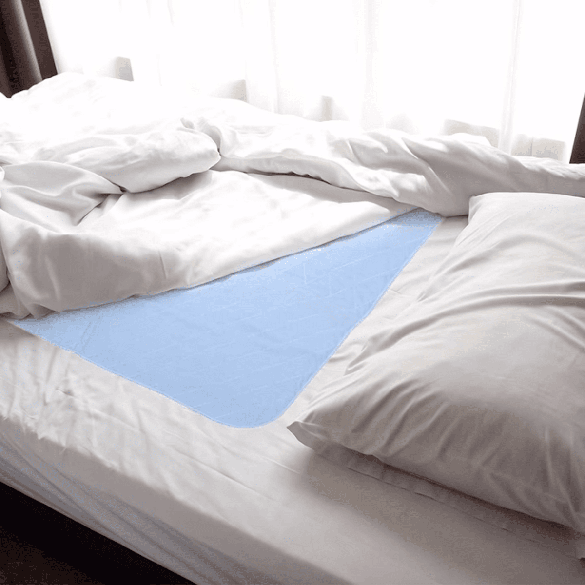 Light blue washable underpad laid over a bed mattress, quilted waterproof layer