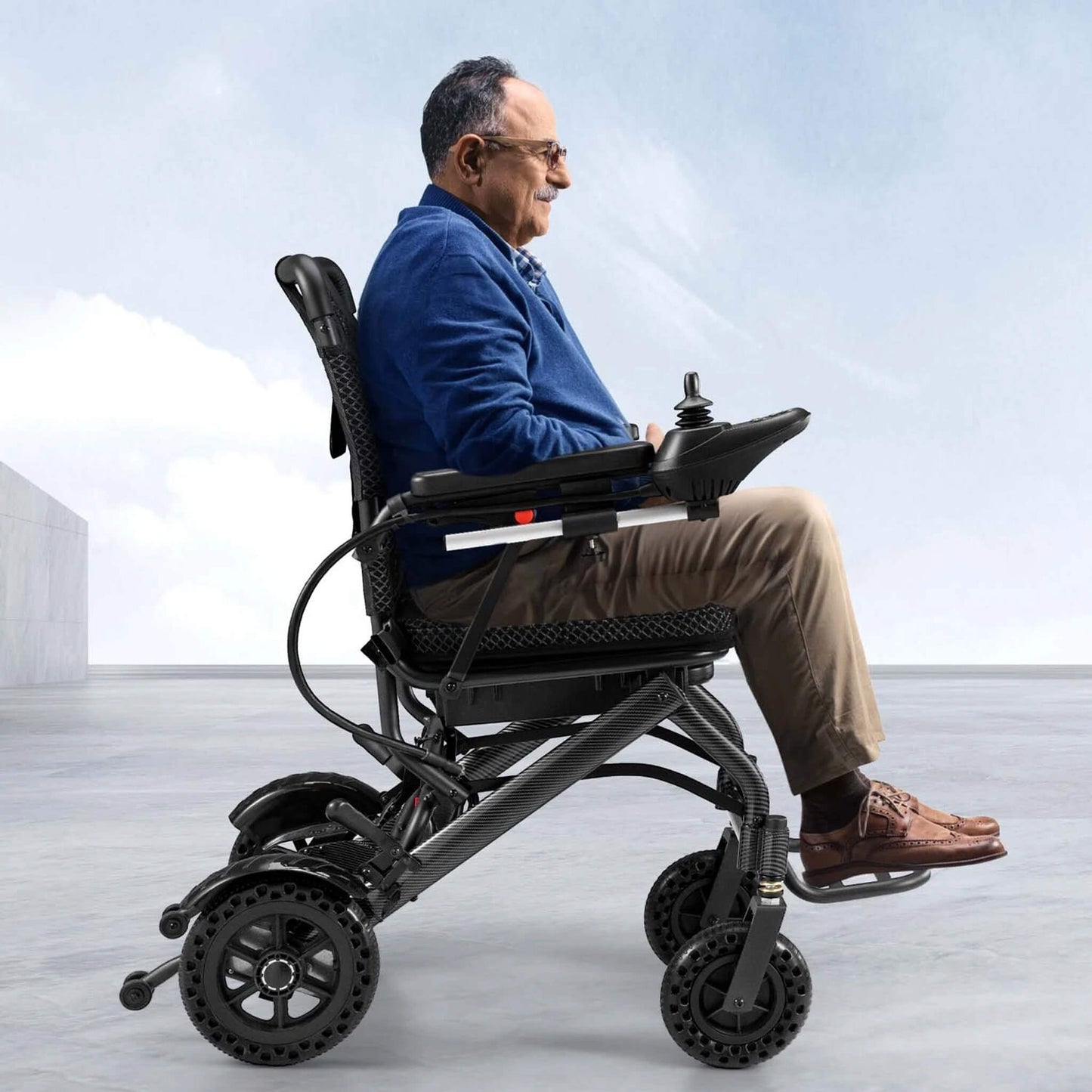 Electric wheelchair in black showing side profile, footrests and large caster wheels