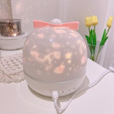 Pink-tinted LED night light projector globe on white base with attached cable