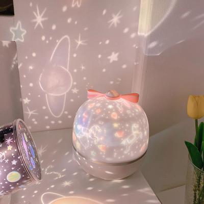 Rotating LED night light projector with glowing pink dome on a white base