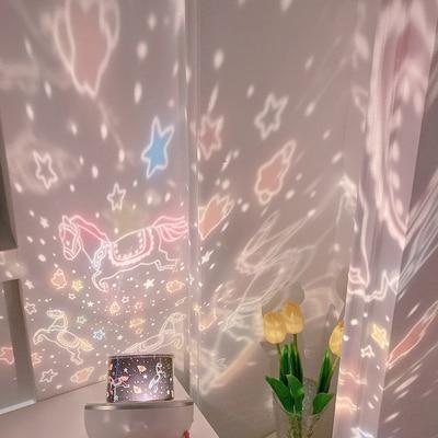 Rotating LED night light projector casting star patterns, pink dome on white base