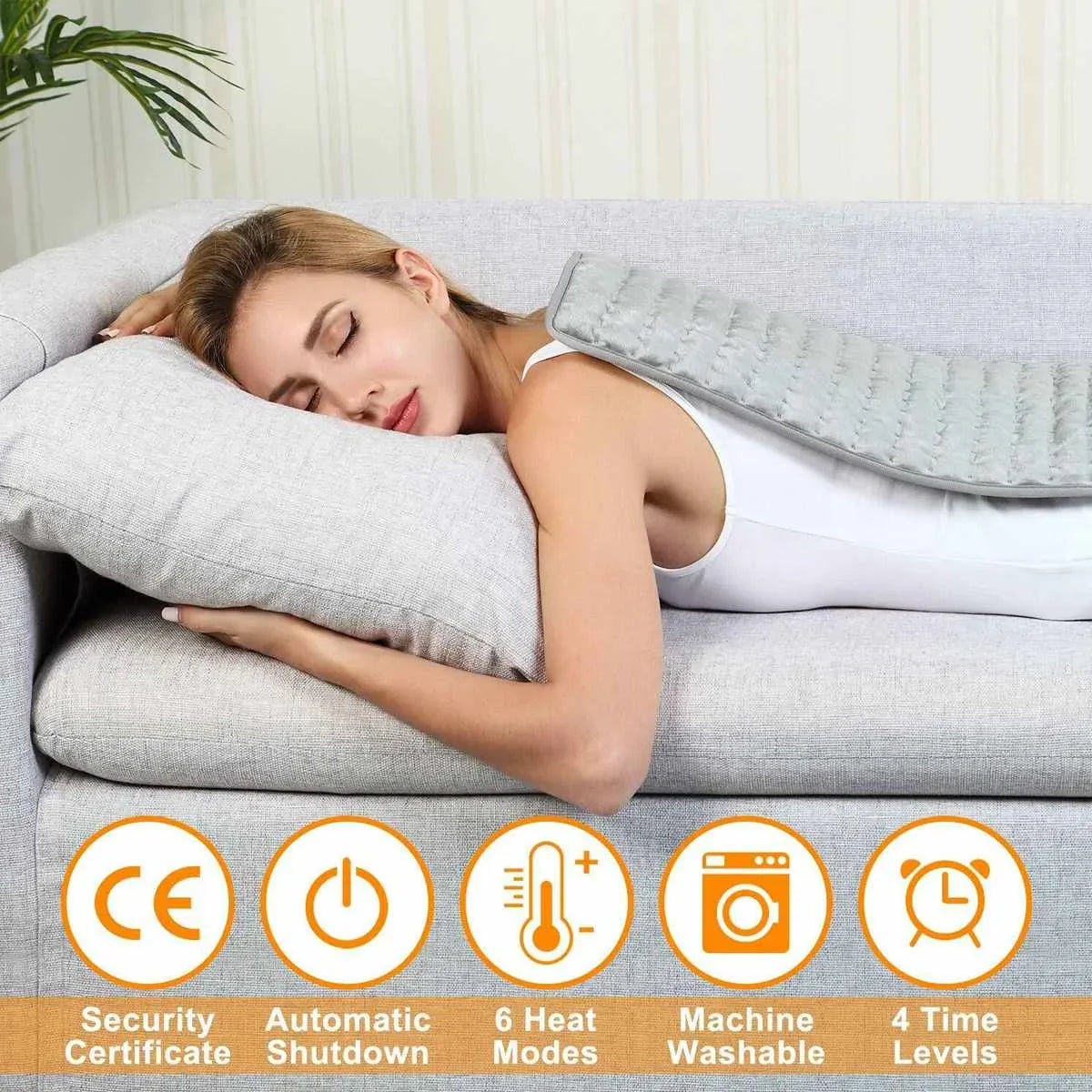Gray electric heating pad resting on a couch cushion with controller visible