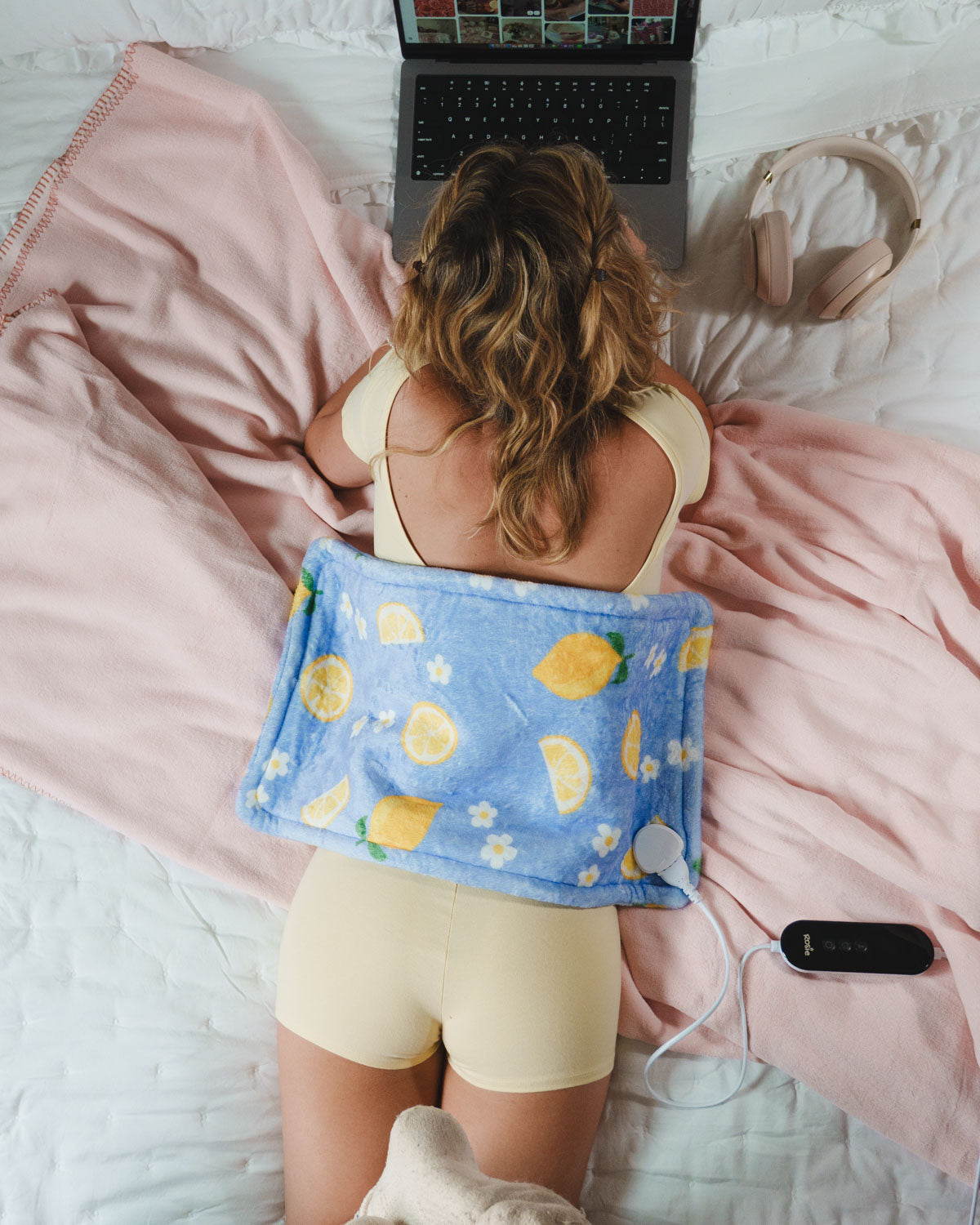 Lemon-pattern blue heating pad with white cord controller near bed