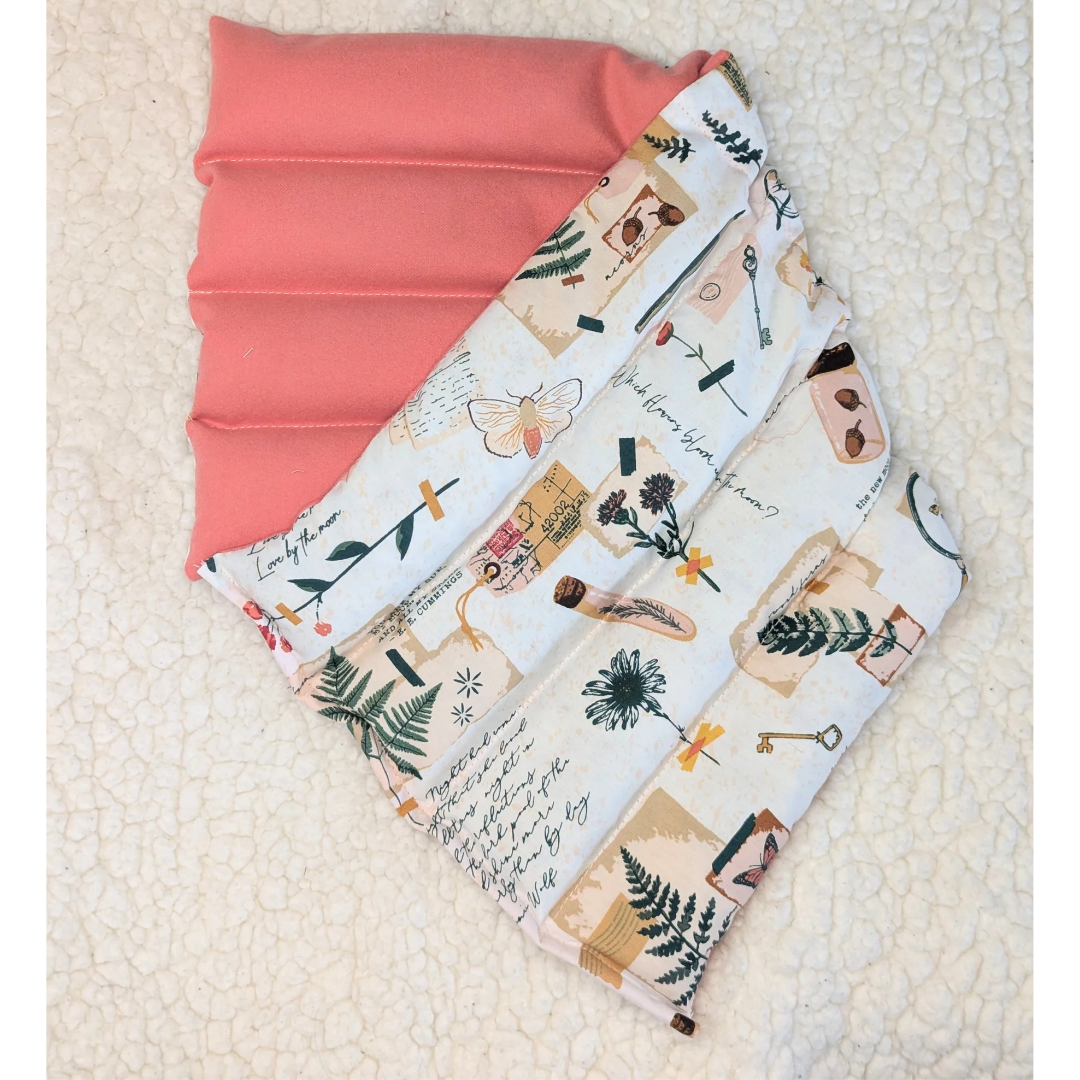 Weighted heating pad with Field Diary print cover folded over pink flannel backing