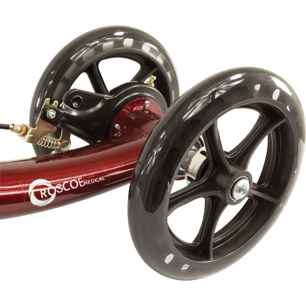 Close-up of burgundy knee scooter wheel and fork with treaded black tires