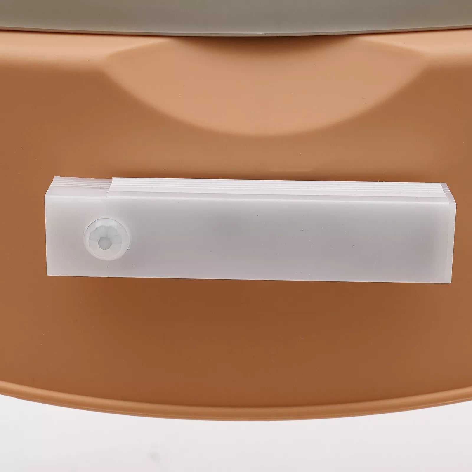 Close-up of khaki commode chair side panel with white pull handle cover