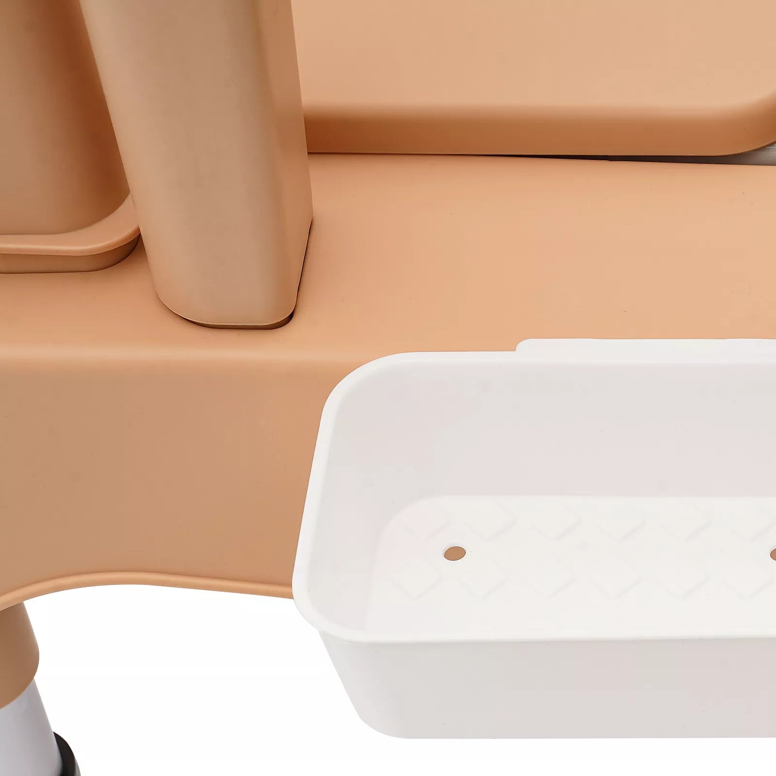 Close-up of white bedside commode liner tray near khaki chair frame