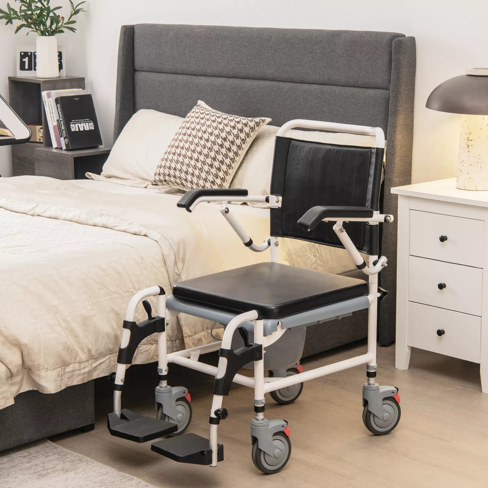 Shower wheelchair beside a bed with black back and seat cushions, armrests, and casters