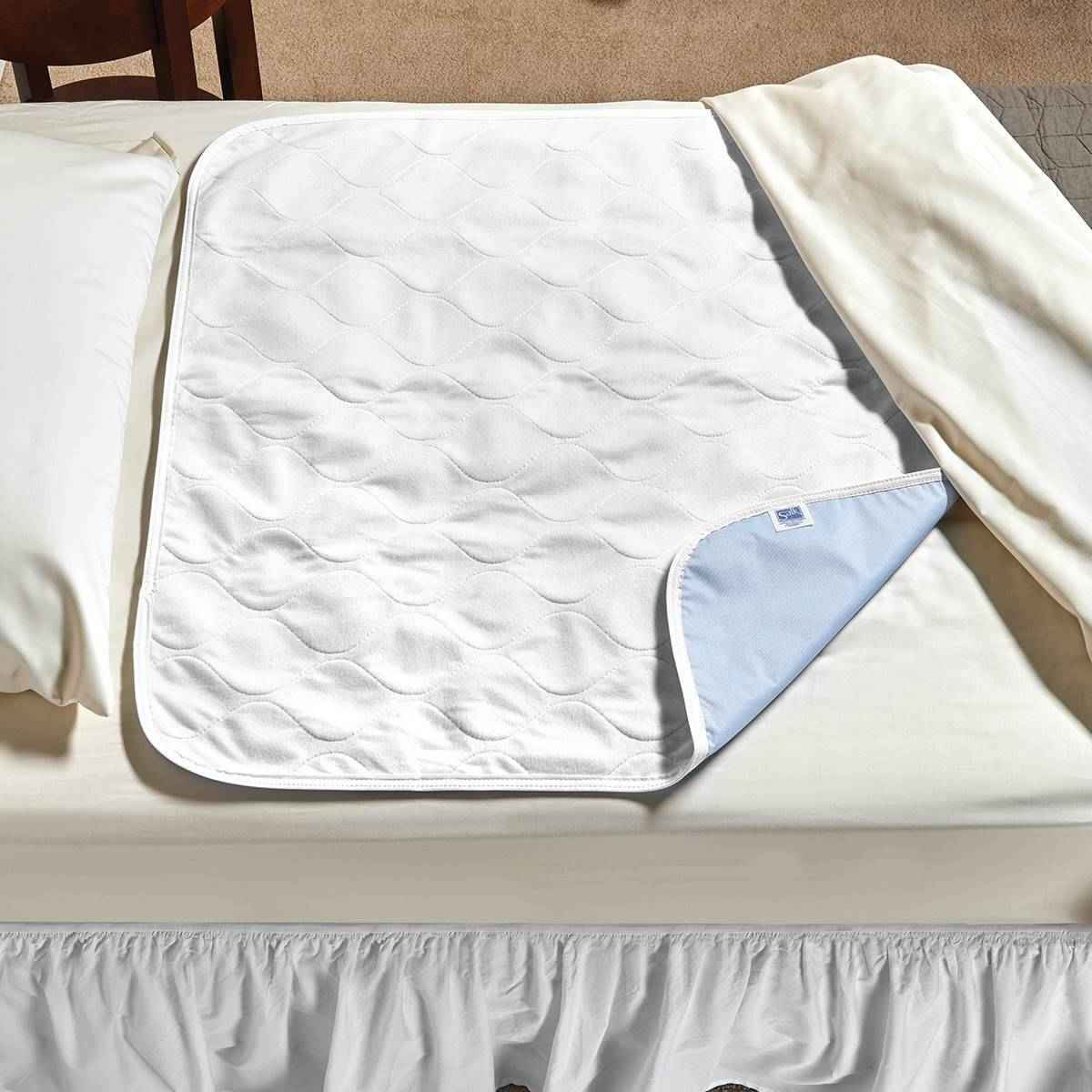 Quilted white underpad with light-blue backing and piped edge, folded for storage