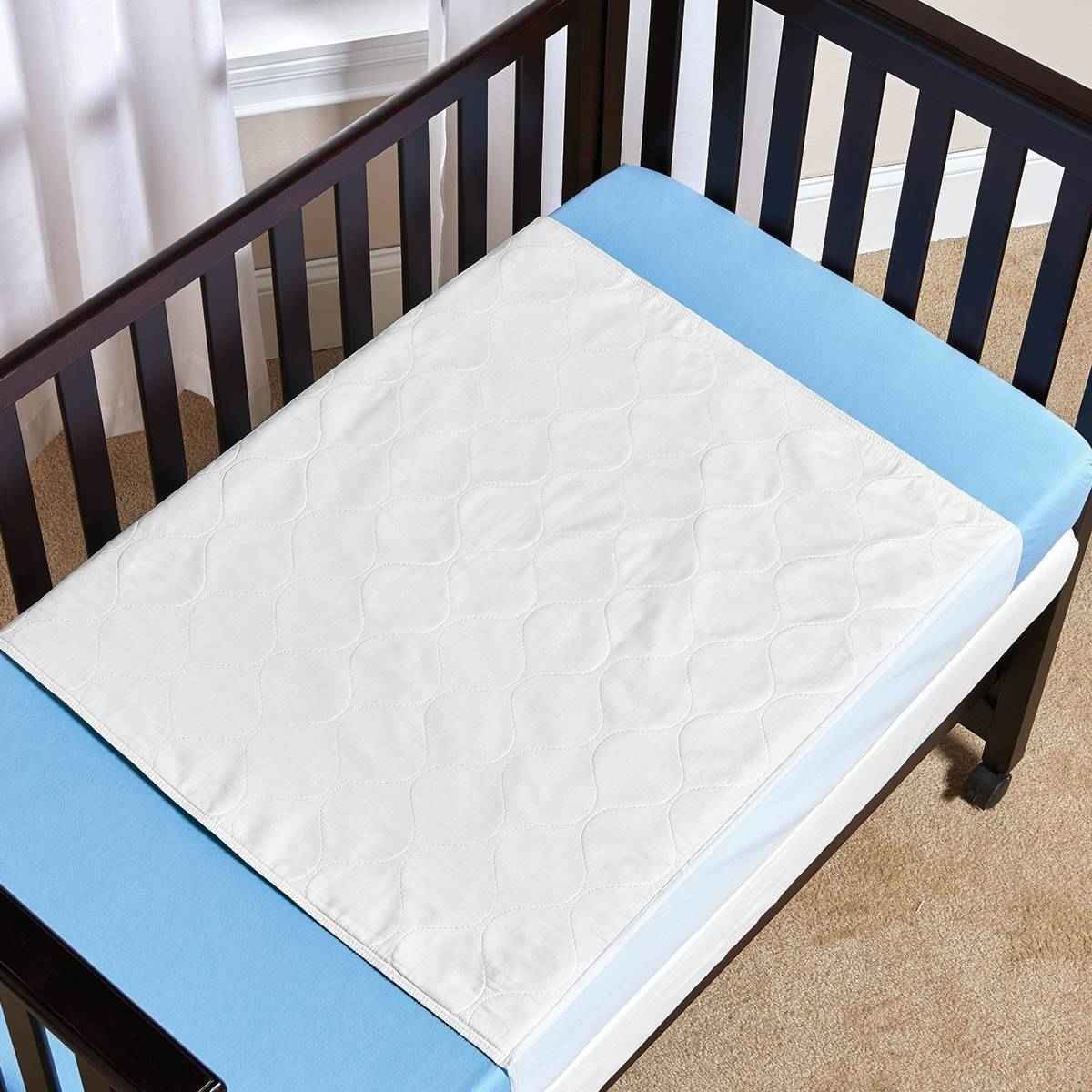 White quilted underpad with light blue border, folded and placed on bed frame