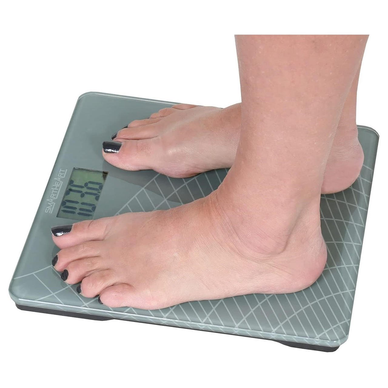 Gray digital weight scale with blue display and bare feet positioned on top