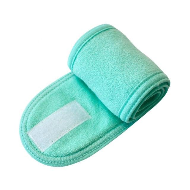 Mint green terry toweling headband with white patch, rolled spa accessory.