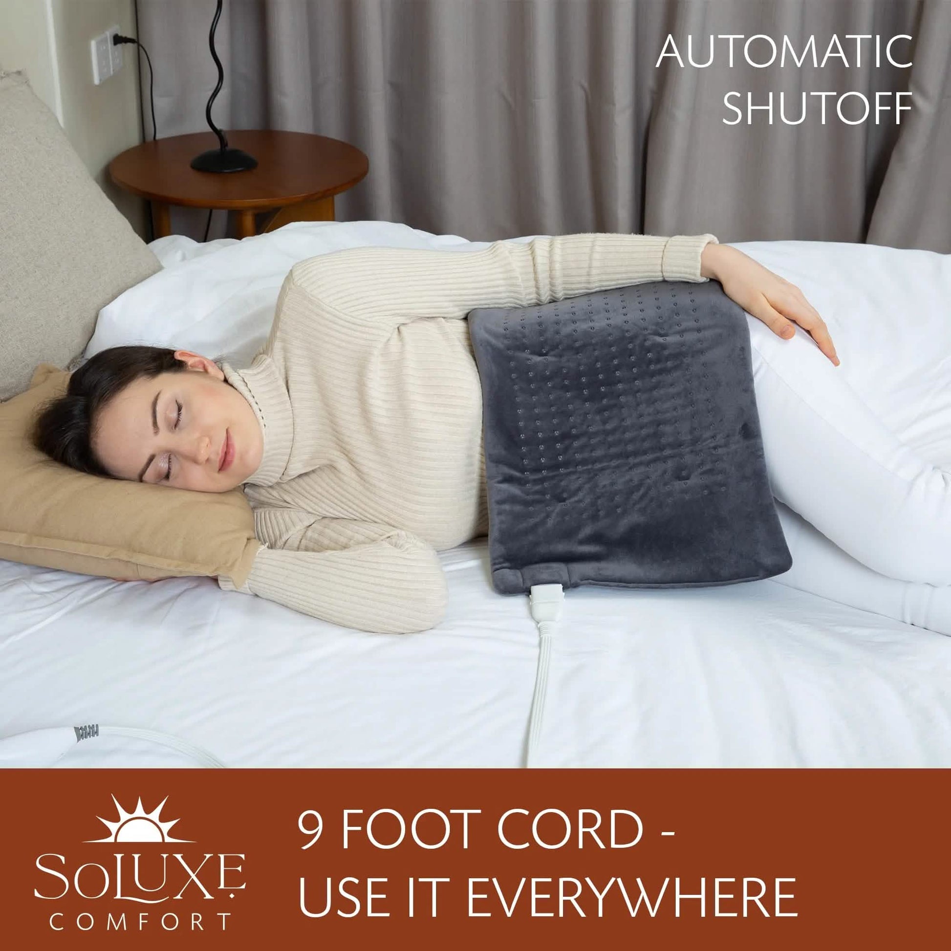 Dark gray heating pad on bed with long white cord for 9-foot reach