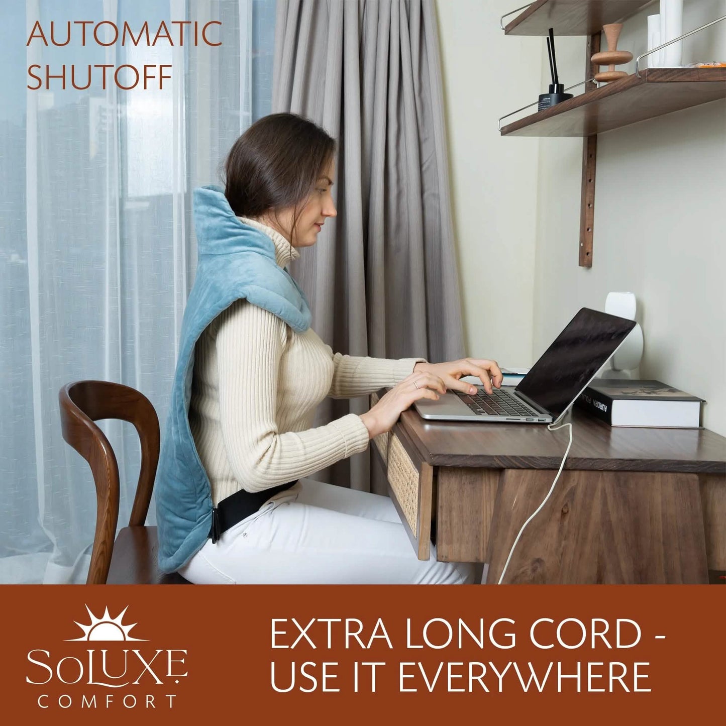 Blue weighted heating pad draped around shoulders while using a laptop