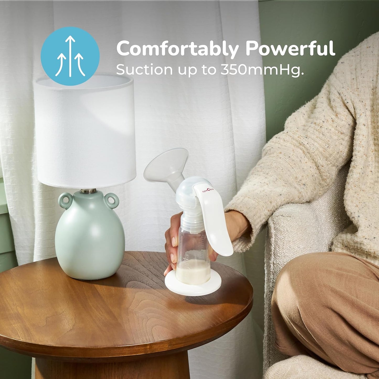 Manual breast pump held in hand with bottle and suction indicator