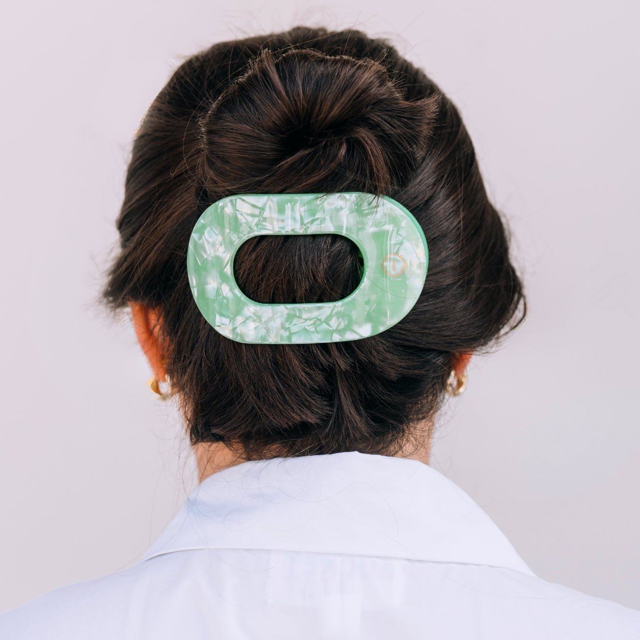 Mint green translucent hair clip placed on a dark hair bun
