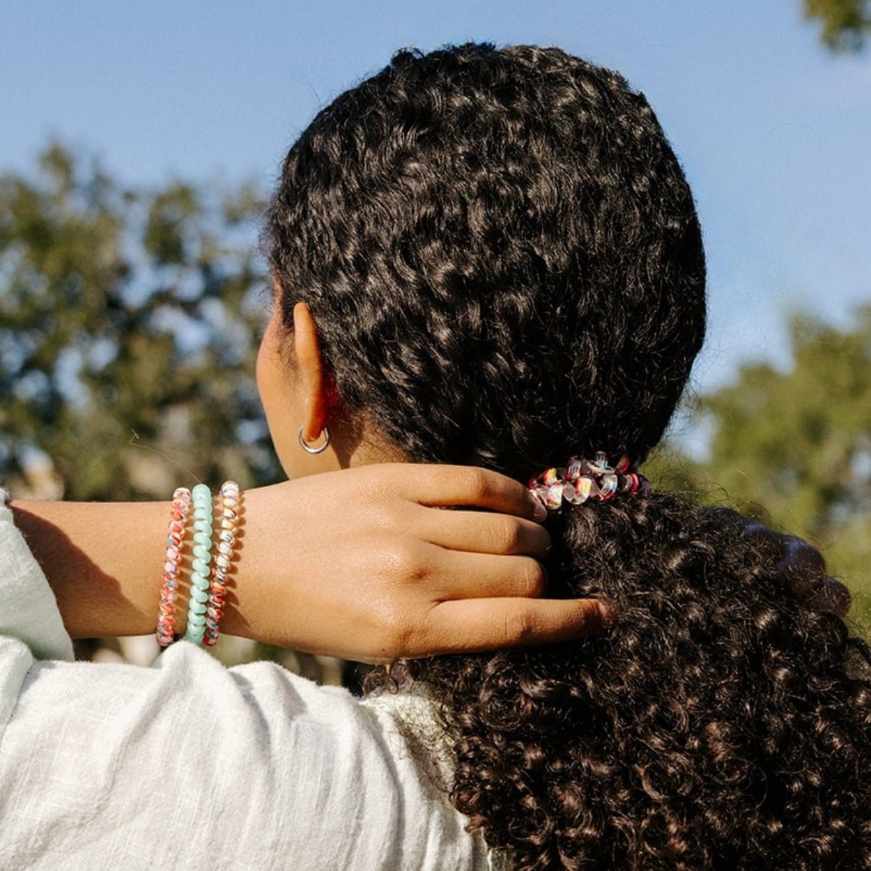 Large spiral hair ties on curly hair in mint, clear pink, and striped pink
