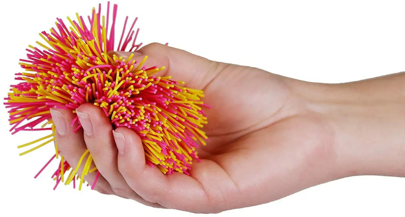 Hand squeezing a pink and yellow 3 inch standard Koosh ball
