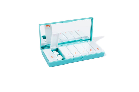 Teal pill box with open lid and lettered slots for weekly medication