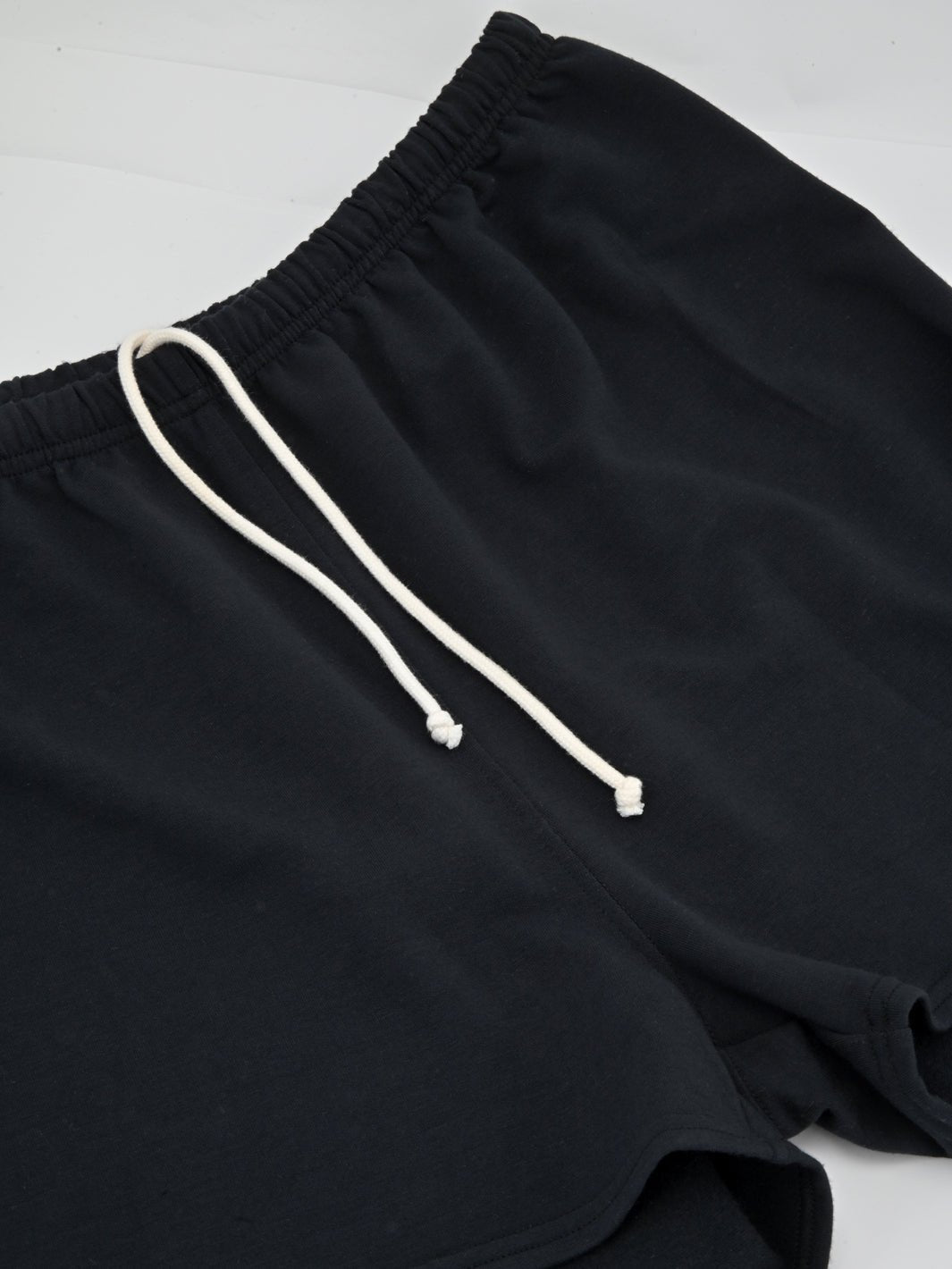 Black sweatshorts close-up: elastic waistband and white drawstring ties