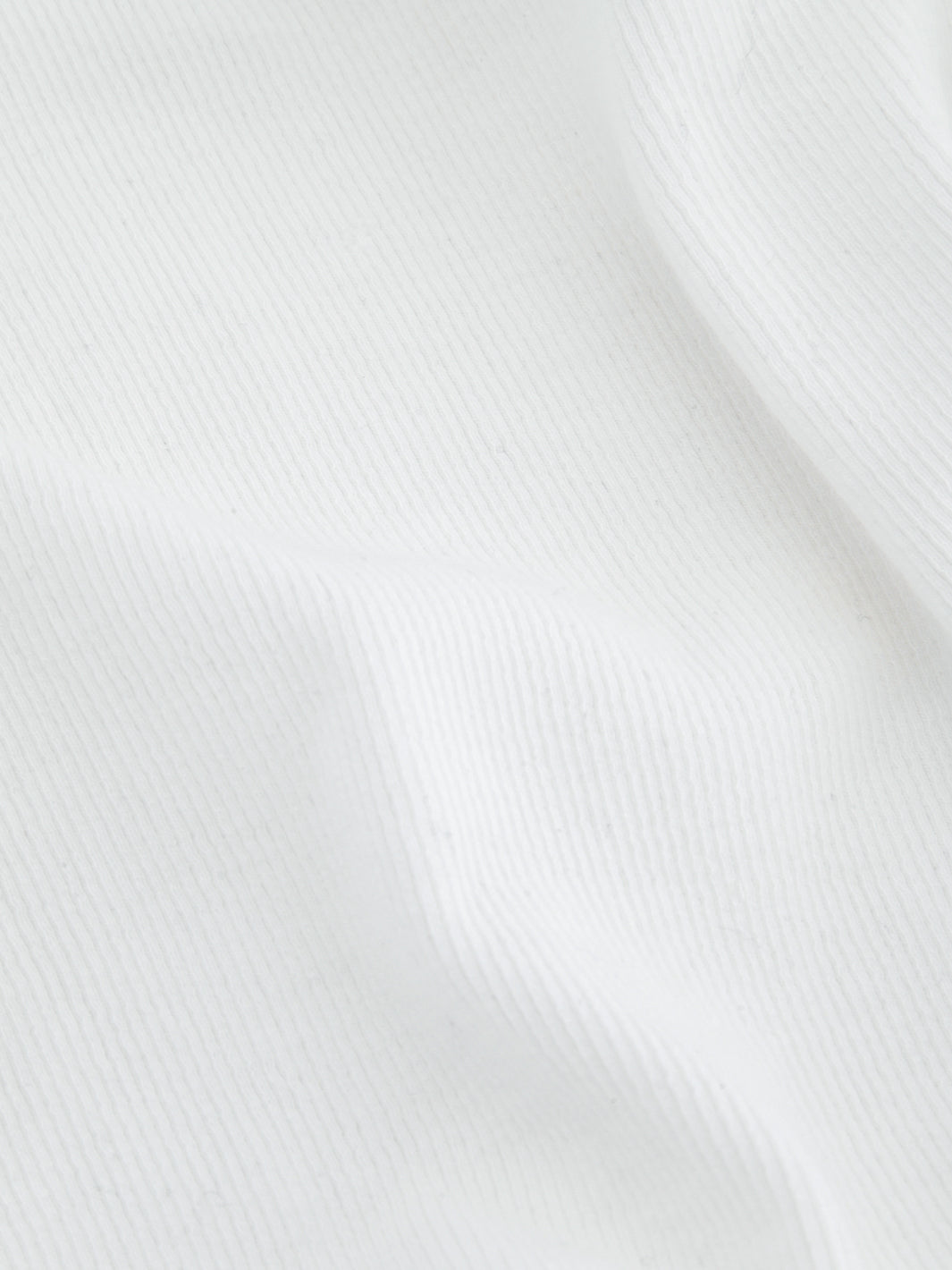 Close-up of white ribbed knit fabric with vertical texture