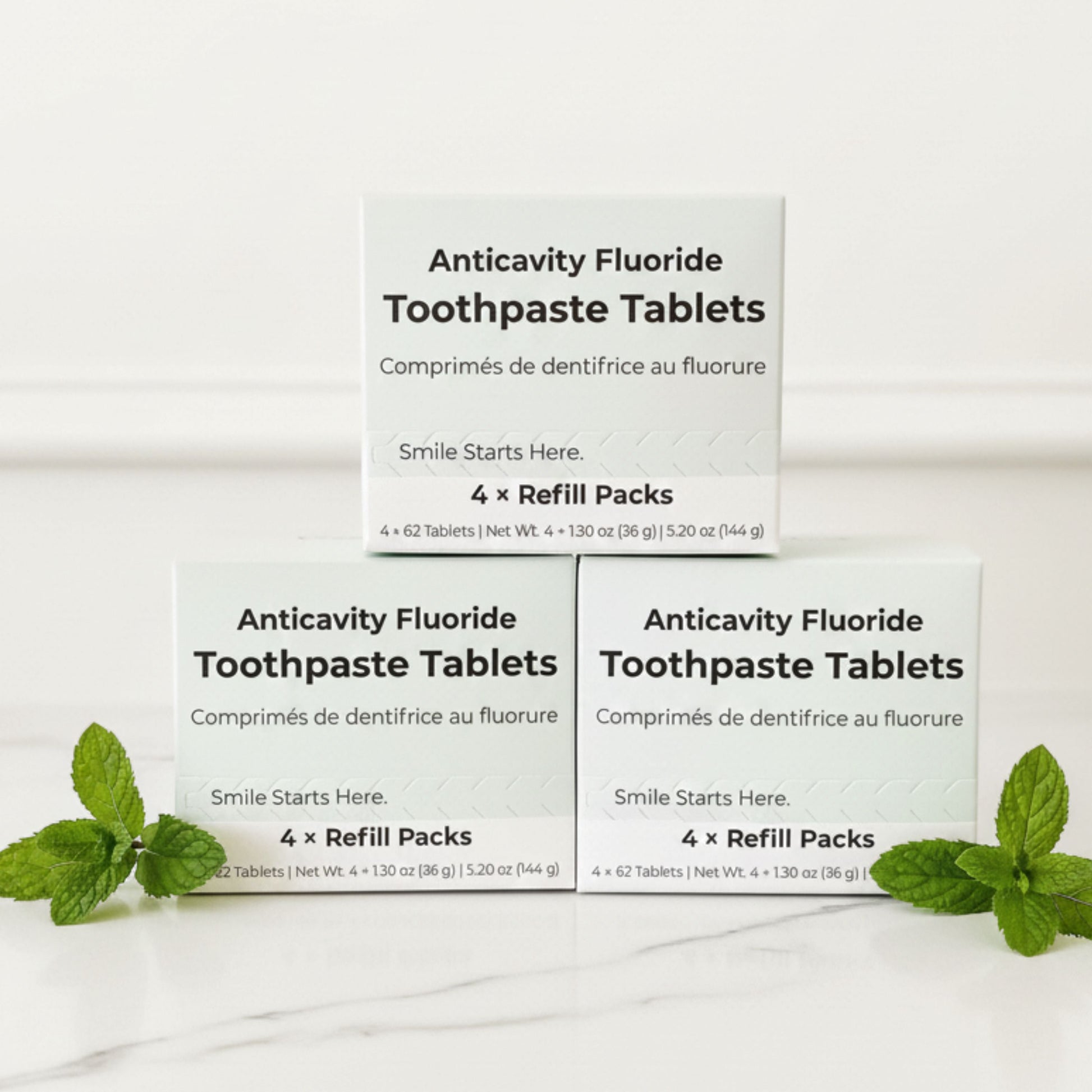 Fluoride toothpaste tablet refill pack boxes stacked with mint leaves