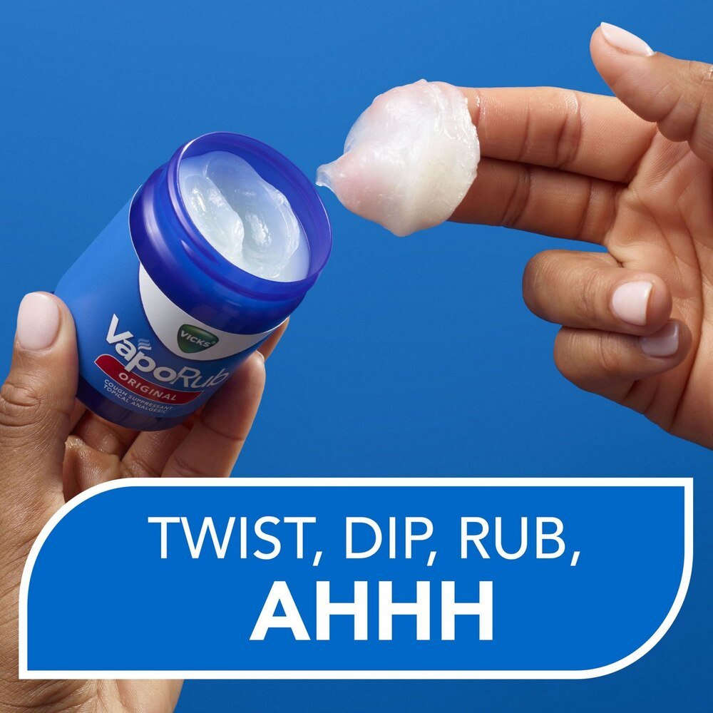 Open VapoRub jar with white ointment dollop on fingertip