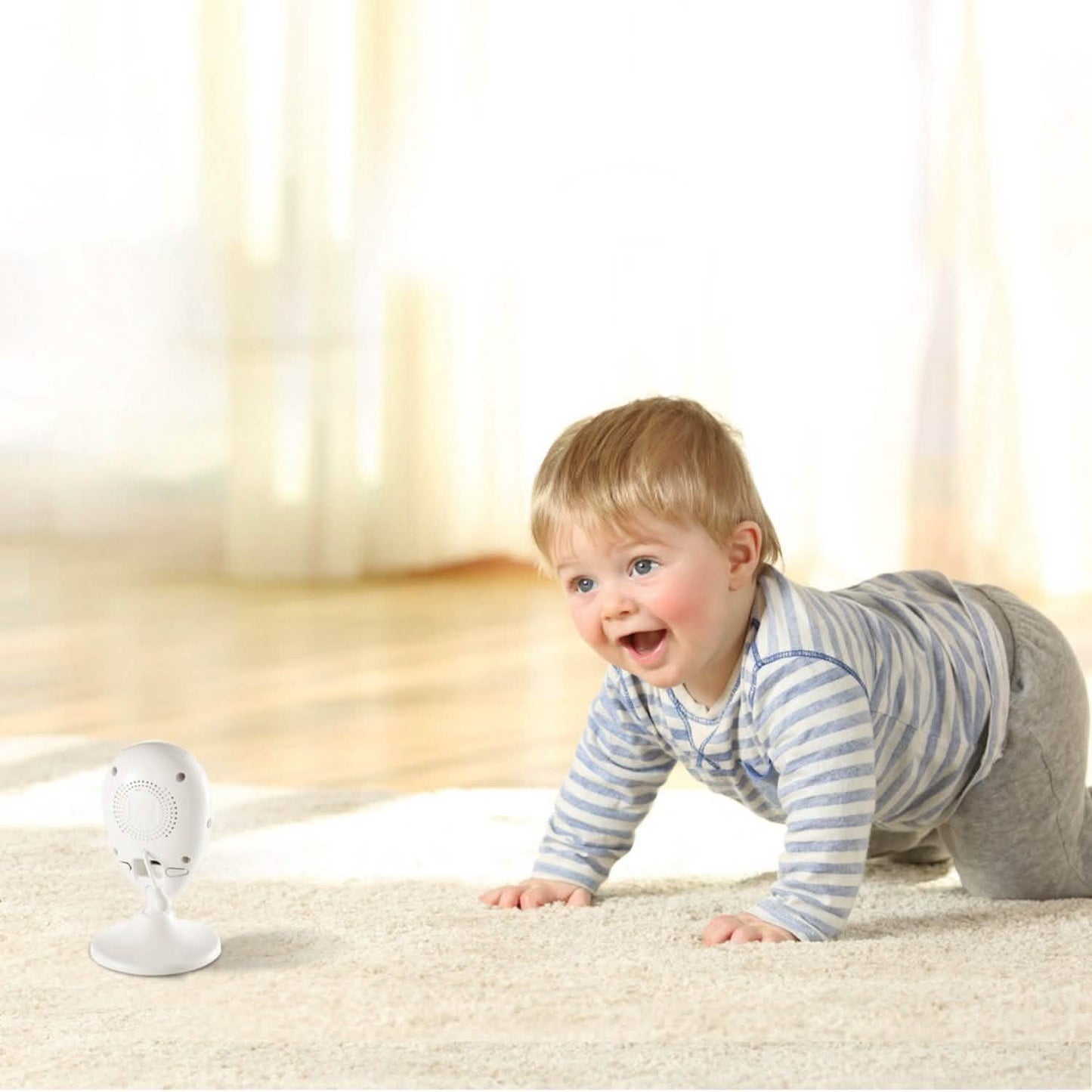 White baby monitor camera on stand near a toddler crawling on the floor